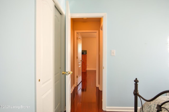 hallway featuring baseboards and wood finished floors