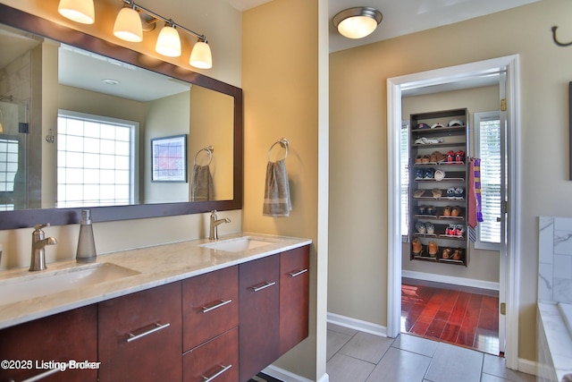 full bathroom with double vanity, baseboards, a sink, and tile patterned flooring