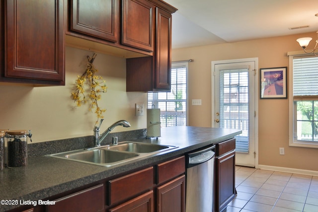 kitchen featuring stainless steel dishwasher, light tile patterned flooring, dark countertops, and a sink