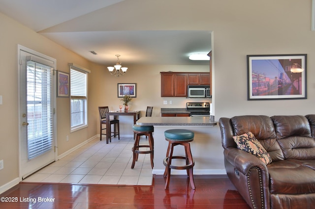 kitchen with a peninsula, open floor plan, a kitchen bar, appliances with stainless steel finishes, and a notable chandelier