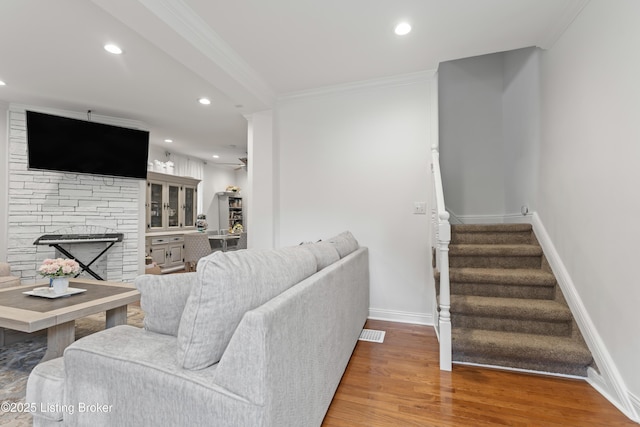 living area featuring stairs, wood finished floors, a fireplace, baseboards, and recessed lighting