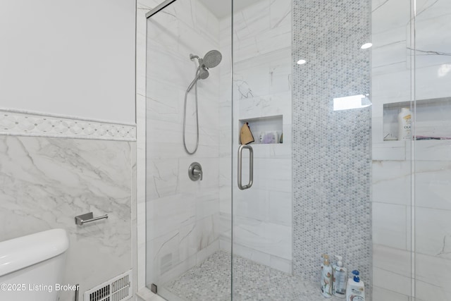 full bath with tile walls, a stall shower, toilet, and visible vents