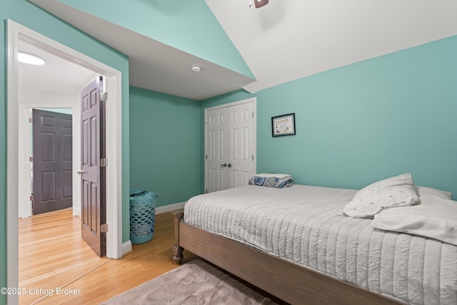 bedroom with a closet, lofted ceiling, baseboards, ceiling fan, and light wood finished floors