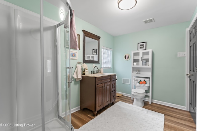 bathroom with visible vents, wood finished floors, toilet, and a shower stall