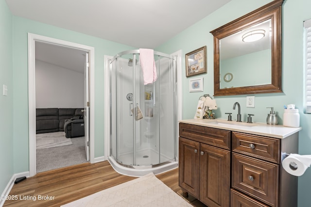 bathroom featuring vanity, baseboards, a shower stall, and wood finished floors