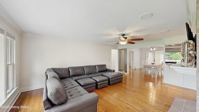 living area featuring crown molding, light wood finished floors, ceiling fan, and baseboards
