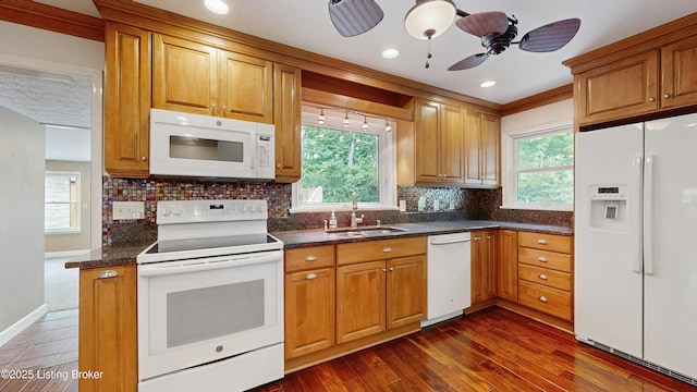 kitchen featuring decorative backsplash, a ceiling fan, brown cabinets, a sink, and white appliances