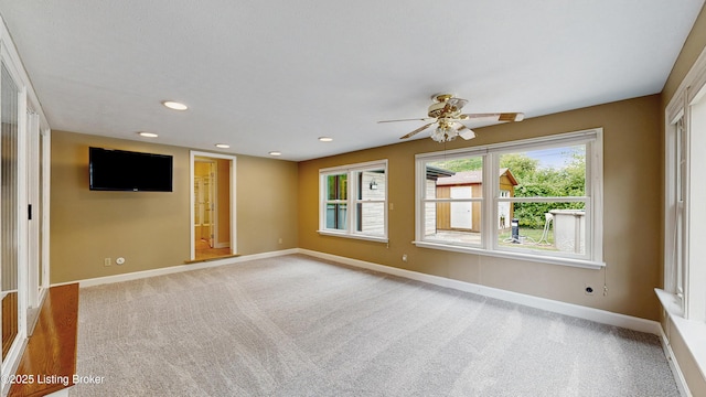 empty room with ceiling fan, light colored carpet, and baseboards