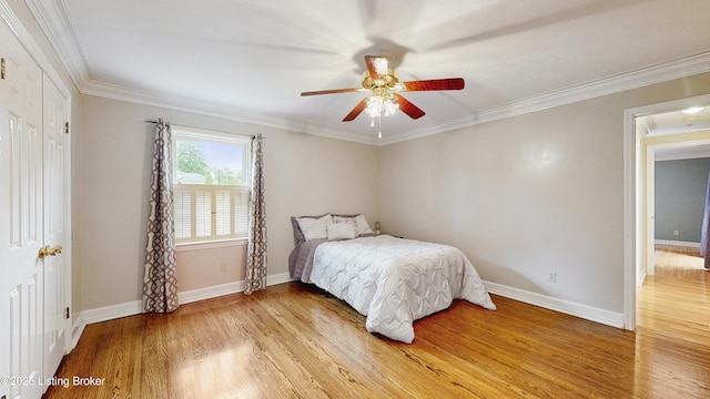 bedroom with light wood-style floors, ornamental molding, and baseboards