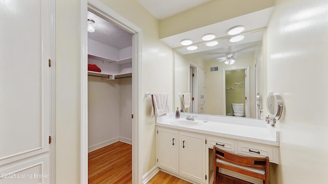 bathroom with a ceiling fan, visible vents, wood finished floors, vanity, and toilet