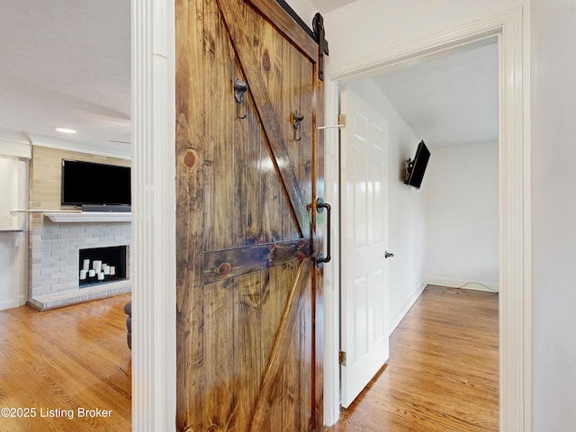 corridor featuring baseboards, a barn door, and wood finished floors