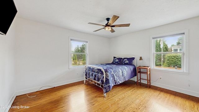 bedroom with light wood-style floors, baseboards, and ceiling fan