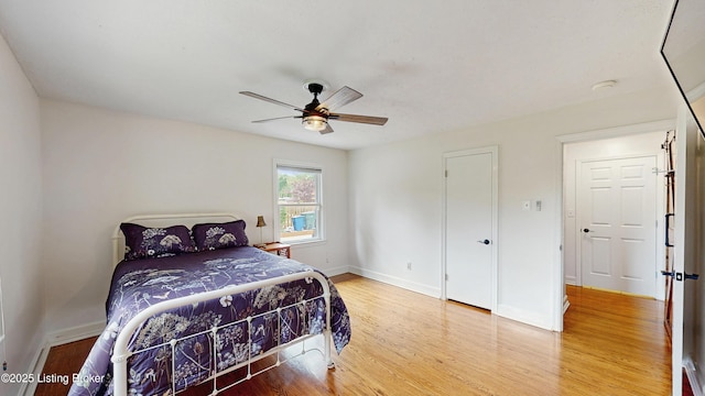 bedroom with a ceiling fan, baseboards, and wood finished floors
