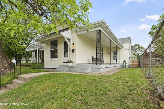 bungalow-style house featuring a porch, brick siding, a fenced backyard, and a front lawn