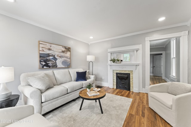 living room featuring a fireplace, wood finished floors, baseboards, ornamental molding, and recessed lighting
