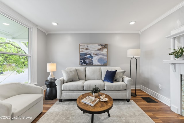 living area featuring visible vents, baseboards, crown molding, and wood finished floors
