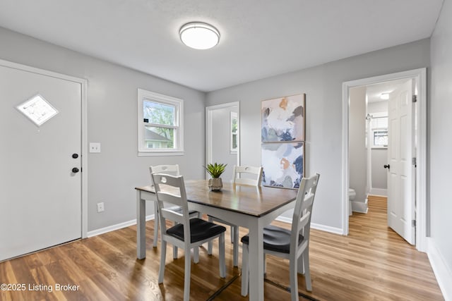 dining room featuring baseboards, light wood-type flooring, and a wealth of natural light
