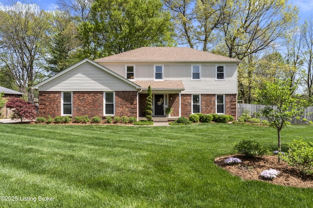 traditional home featuring fence, a shingled roof, a front lawn, and brick siding