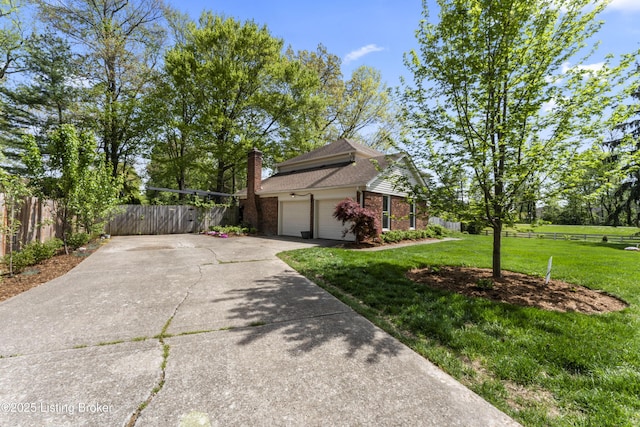 view of side of home with fence, brick siding, a chimney, a lawn, and driveway