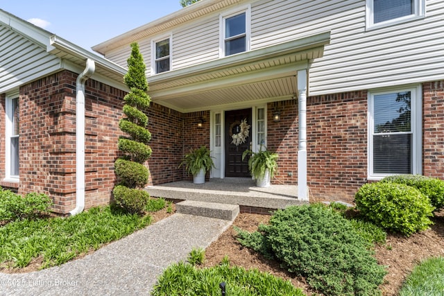 doorway to property featuring brick siding and a porch