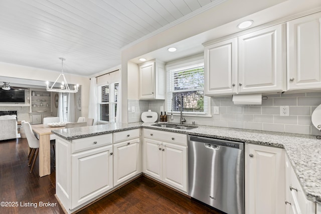kitchen featuring tasteful backsplash, dishwasher, a sink, a peninsula, and white cabinetry