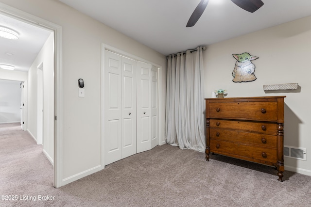 carpeted bedroom with ceiling fan, baseboards, and a closet