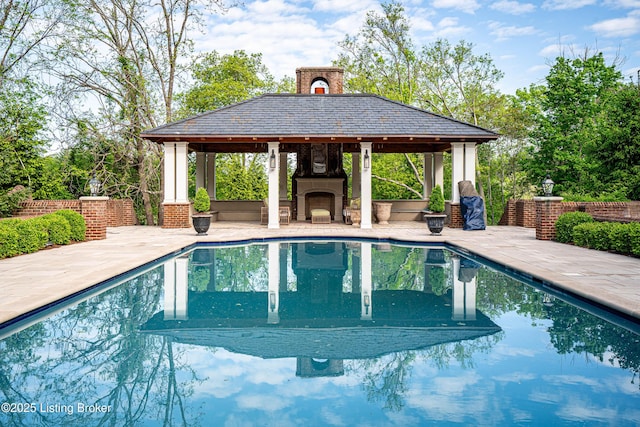outdoor pool with a gazebo, exterior fireplace, and a patio area
