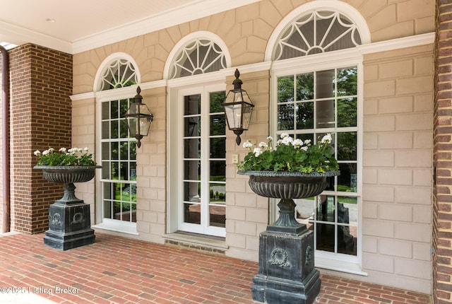 entrance to property featuring a porch and brick siding