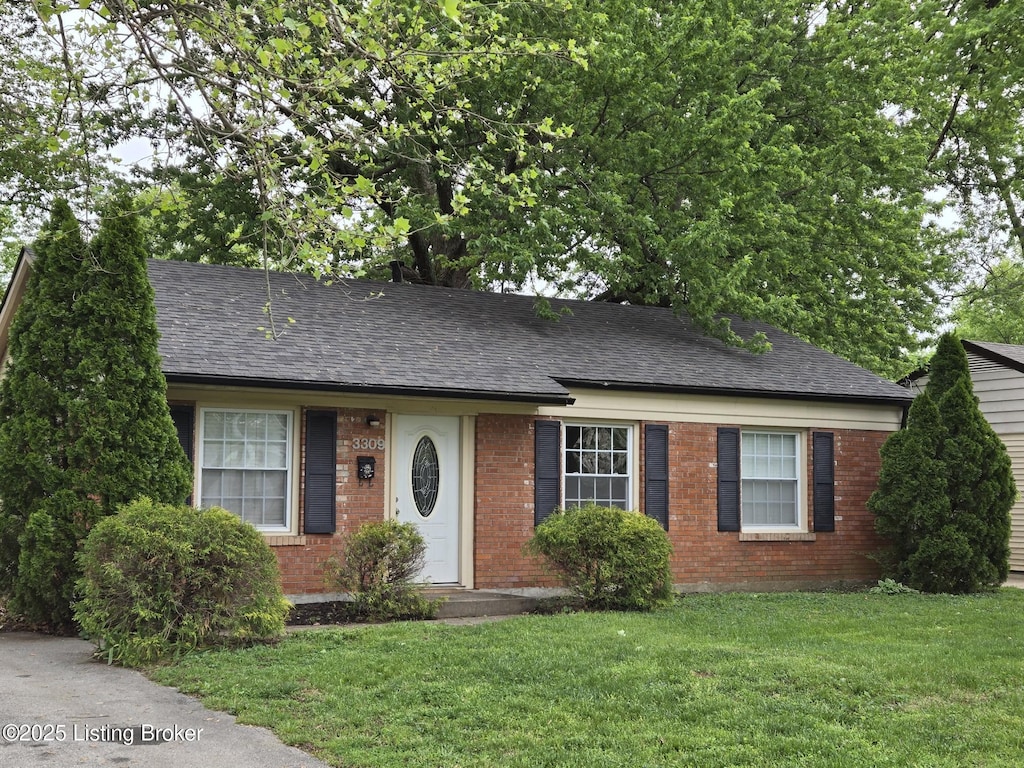 ranch-style home with brick siding, a shingled roof, and a front lawn