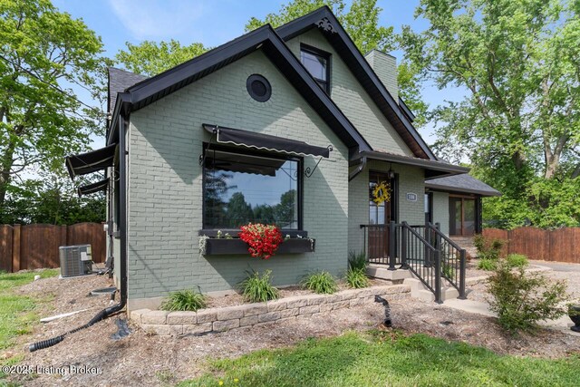 view of front facade with brick siding, fence, and central AC unit