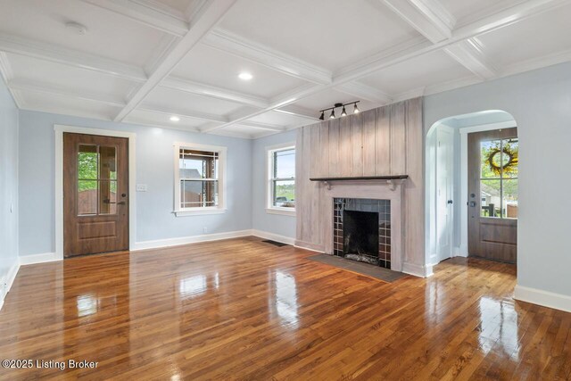 unfurnished living room with arched walkways, baseboards, wood finished floors, and coffered ceiling