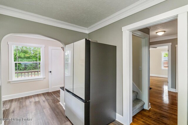 interior space with freestanding refrigerator, arched walkways, a textured ceiling, and wood finished floors