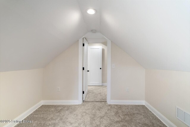 additional living space with carpet floors, baseboards, visible vents, and vaulted ceiling