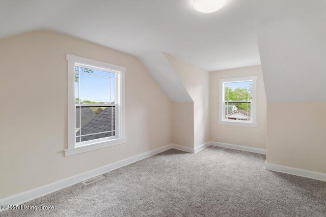 bonus room featuring carpet floors, baseboards, visible vents, and lofted ceiling