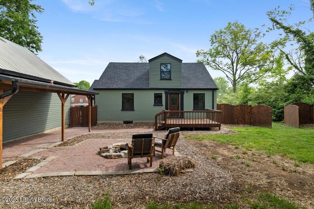 rear view of house with fence, a wooden deck, an outdoor fire pit, and a patio area