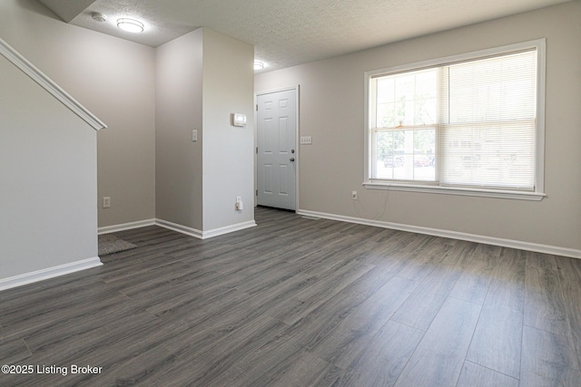unfurnished living room featuring baseboards, dark wood-style floors, and a textured ceiling