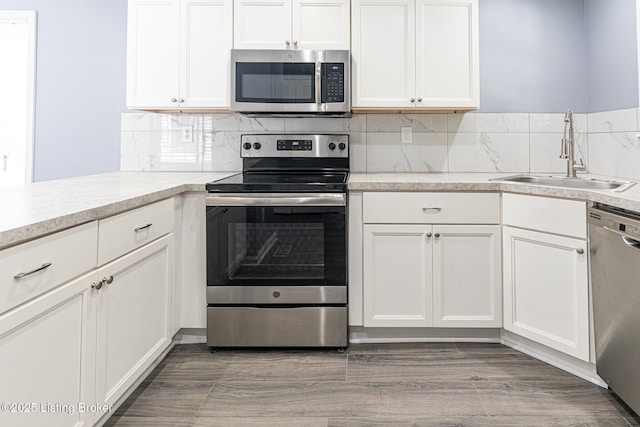 kitchen with light countertops, stainless steel appliances, white cabinetry, and a sink
