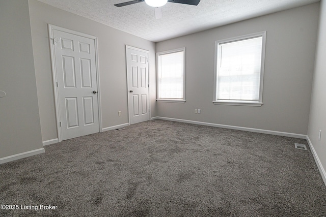 unfurnished bedroom featuring carpet floors, visible vents, baseboards, a textured ceiling, and a ceiling fan