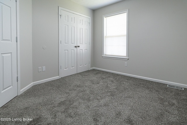 unfurnished bedroom with carpet flooring, baseboards, visible vents, and a closet