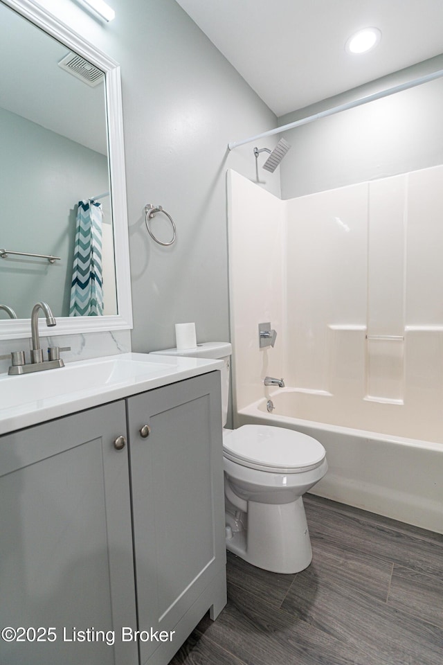 full bathroom featuring vanity, shower / tub combo with curtain, visible vents, wood finished floors, and toilet