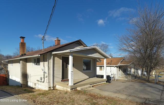 view of front of home with a porch, fence, and a chimney