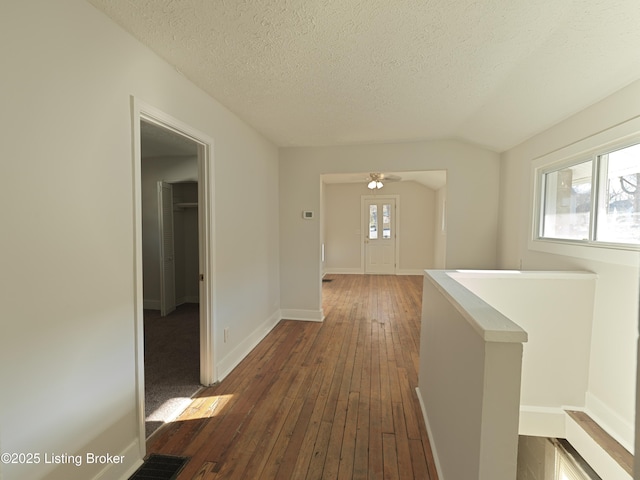 hall with baseboards, a textured ceiling, dark wood-style flooring, and an upstairs landing