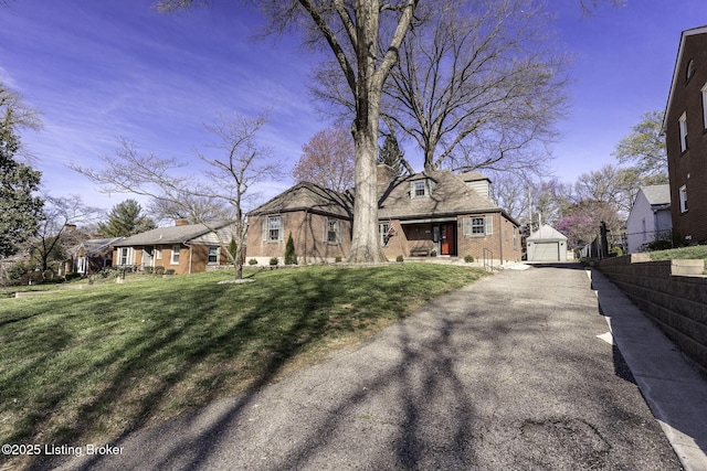 view of front facade featuring an outdoor structure, a garage, a front yard, brick siding, and a residential view