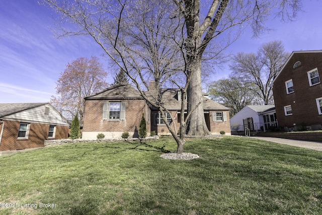 view of front facade featuring a chimney, a front lawn, and brick siding