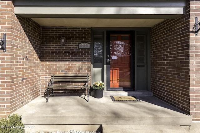 entrance to property with a porch and brick siding