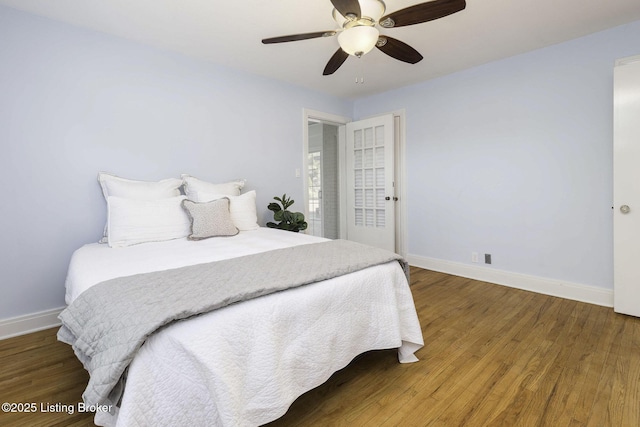 bedroom featuring a ceiling fan, baseboards, and wood finished floors