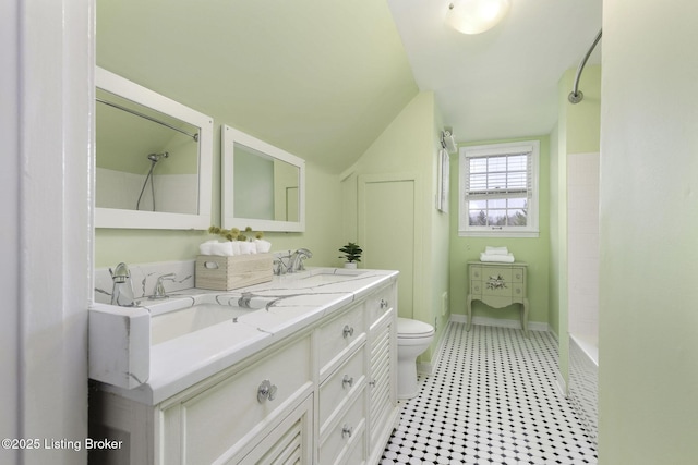 bathroom featuring double vanity, toilet, walk in shower, and a sink