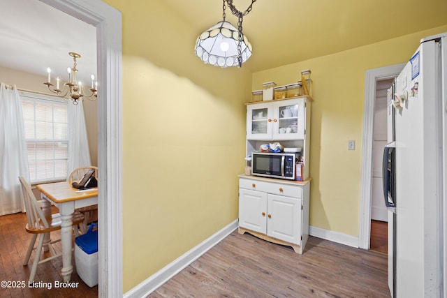 1042 Parkway Dr, Louisville, KY 40217 - interior space featuring wood finished floors, baseboards, stainless steel microwave, freestanding refrigerator, and a notable chandelier