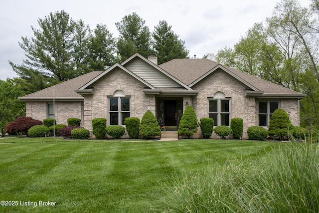 view of front facade featuring brick siding, a front lawn, roof with shingles, and a chimney