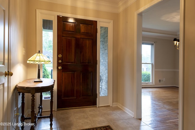 foyer with crown molding, baseboards, and visible vents